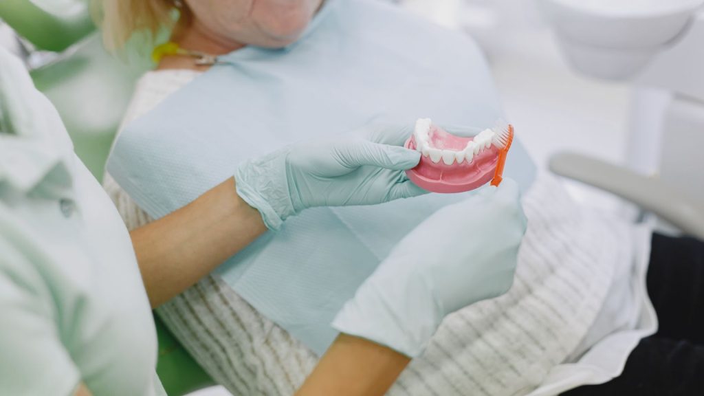 Dentist showing an overdenture model to a senior patient near West Palm Beach