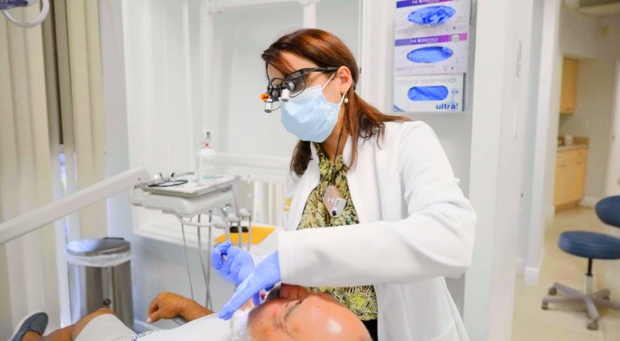 Dentist treating a patient in a treatment room at Cagigas Dental in Lake Worth, FL